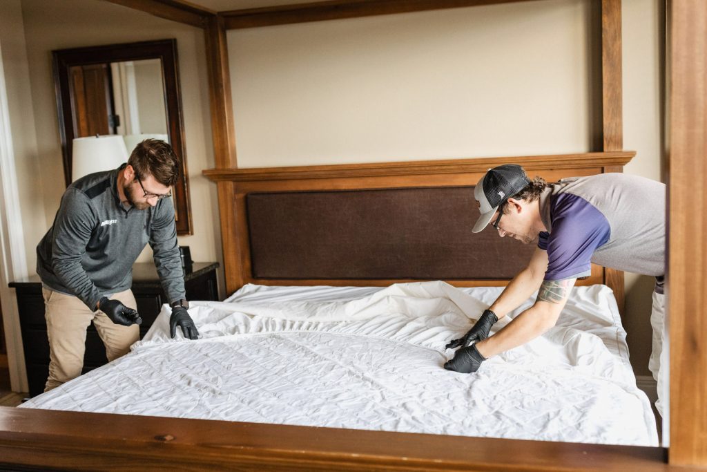 Two techs inspecting a bed for bed bugs again