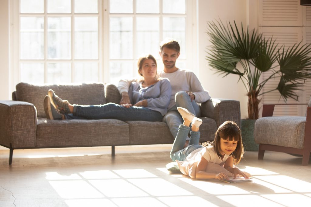 Happy parents relaxing on couch in comfort light living room